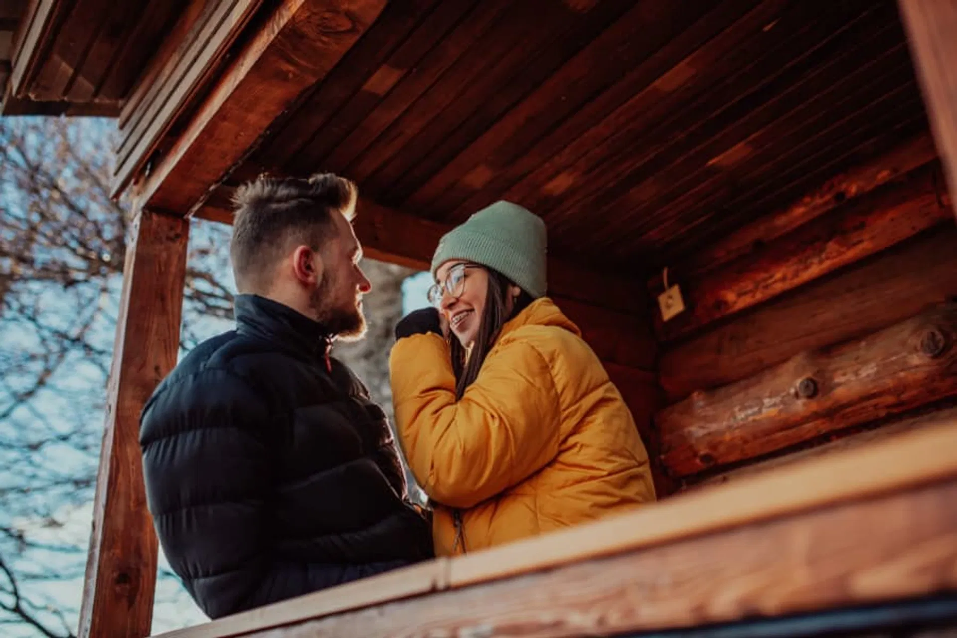 Couple standing outside a cabin smiling at eachother